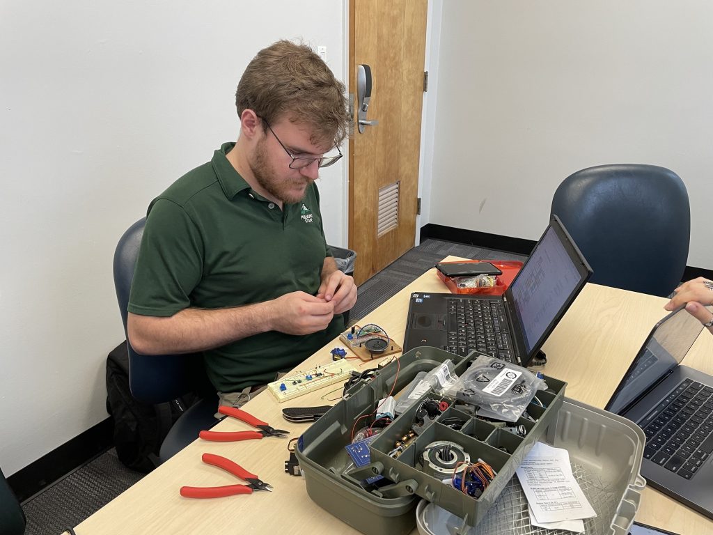 Parrotronix team members working with an electronics toolkit.