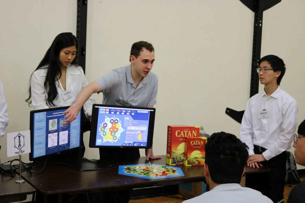 Team Tactica presenting their simulation on two computer monitors.