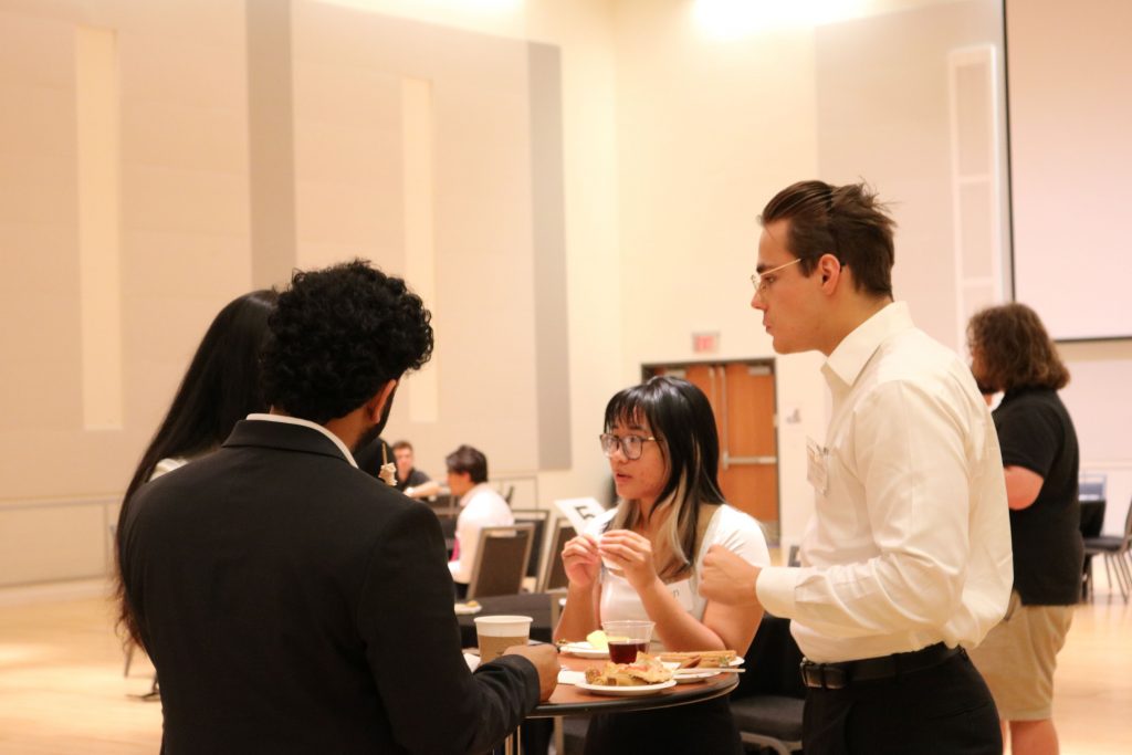 Han and Max in the Reitz Union Rion Ballroom talking with other students.